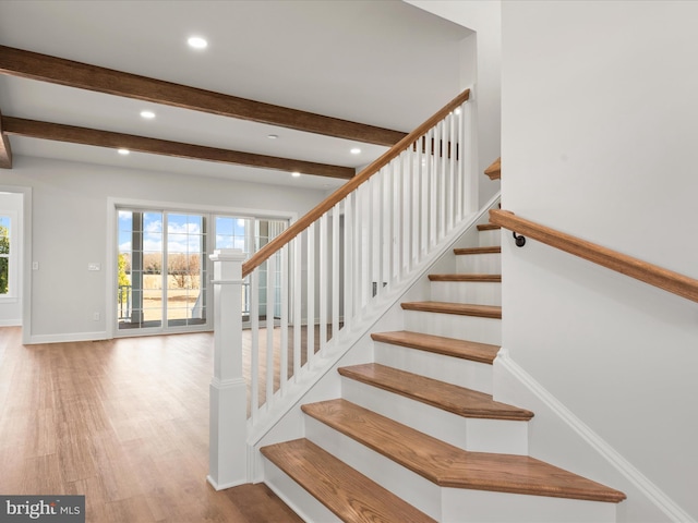 stairway featuring beam ceiling and hardwood / wood-style floors