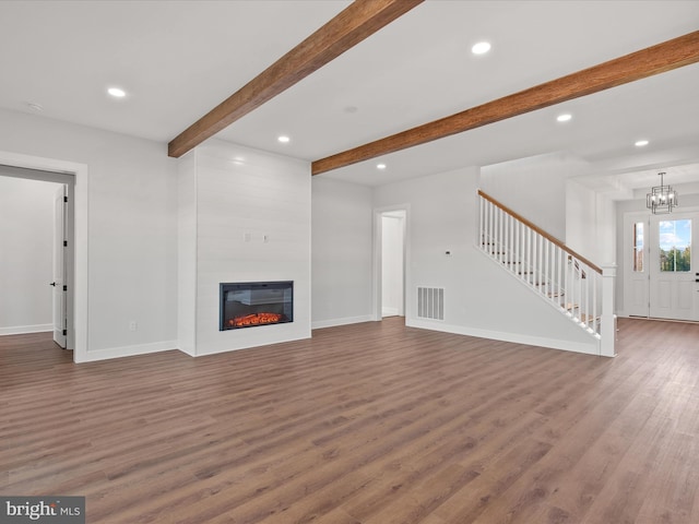 unfurnished living room featuring beamed ceiling, a large fireplace, dark hardwood / wood-style flooring, and a chandelier