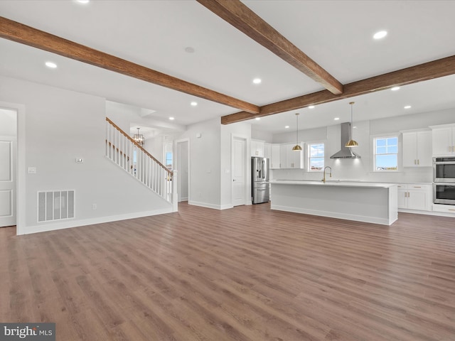 unfurnished living room with beam ceiling, hardwood / wood-style flooring, an inviting chandelier, and sink