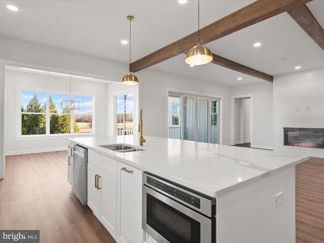 kitchen featuring beam ceiling, light stone counters, and hanging light fixtures