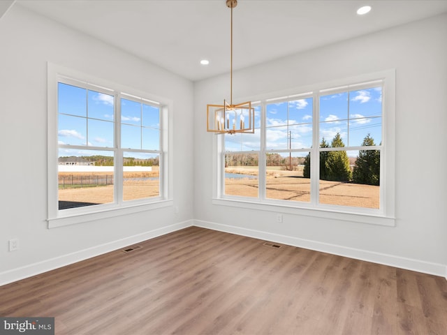 unfurnished dining area with a chandelier and wood-type flooring