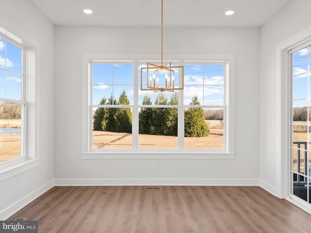 unfurnished dining area with hardwood / wood-style floors and a notable chandelier