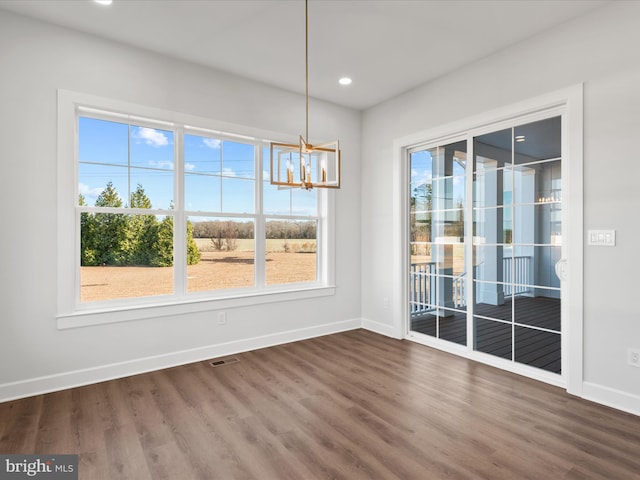 unfurnished dining area featuring dark hardwood / wood-style floors and a notable chandelier