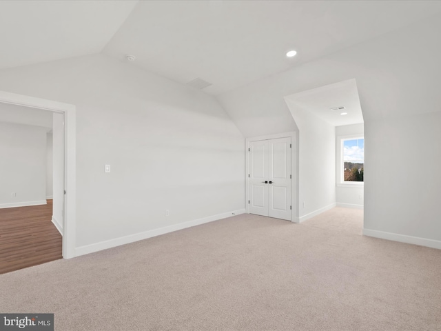 additional living space featuring light carpet and vaulted ceiling