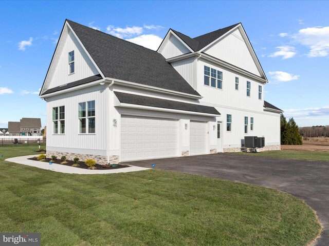 view of front of home with central AC, a front yard, and a garage