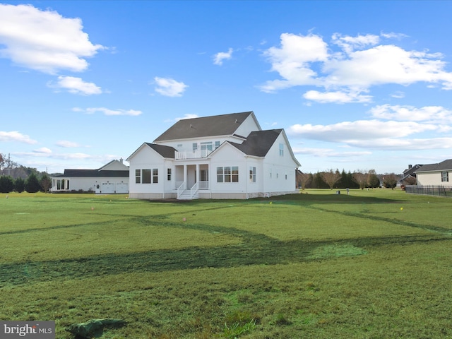 back of house featuring a balcony and a lawn