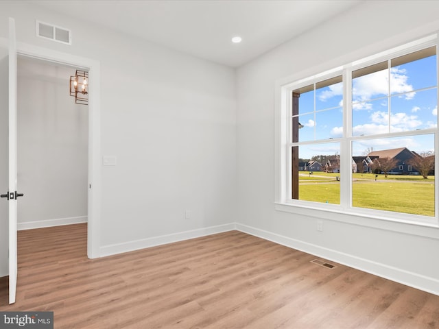 empty room with light hardwood / wood-style flooring and a notable chandelier