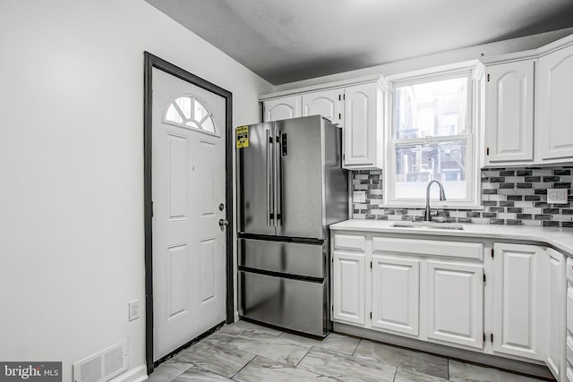 kitchen featuring white cabinets, stainless steel refrigerator, a healthy amount of sunlight, and sink