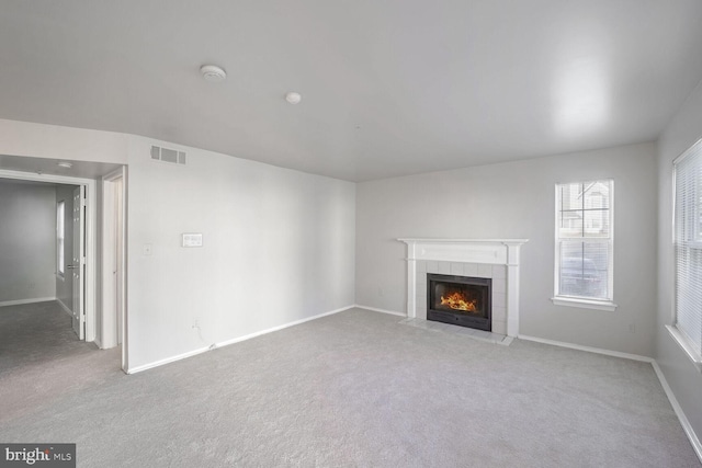 unfurnished living room featuring light carpet and a tile fireplace