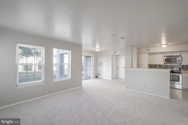 kitchen featuring white cabinets, decorative backsplash, light colored carpet, and stainless steel appliances