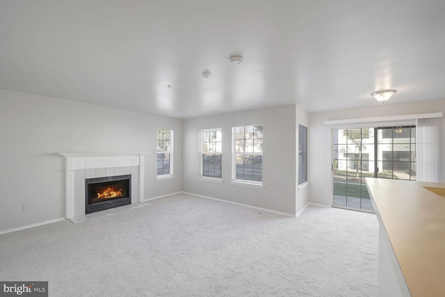 unfurnished living room featuring plenty of natural light, a fireplace, and light carpet