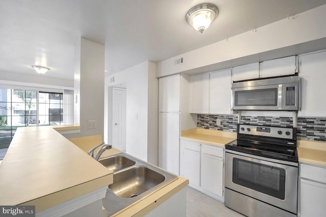 kitchen featuring backsplash, white cabinetry, sink, and appliances with stainless steel finishes