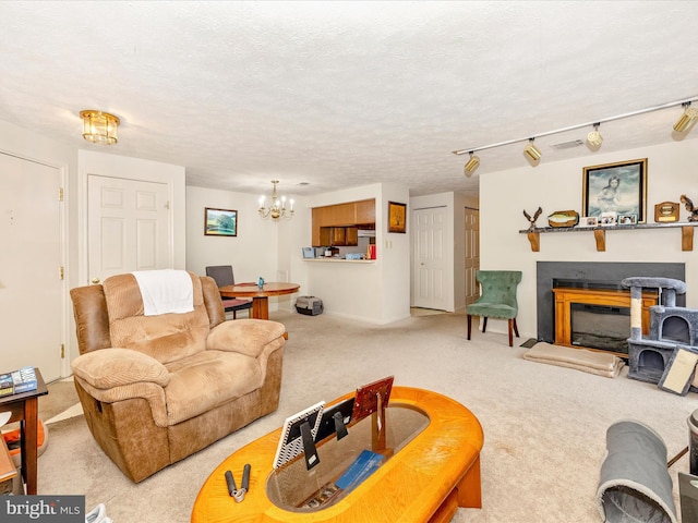 living room with a textured ceiling, carpet floors, a chandelier, and track lighting