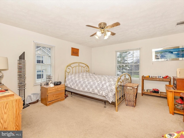 bedroom with a textured ceiling, ceiling fan, and light colored carpet