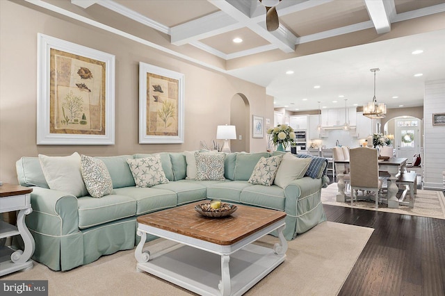 living room with coffered ceiling, crown molding, wood-type flooring, beamed ceiling, and a chandelier