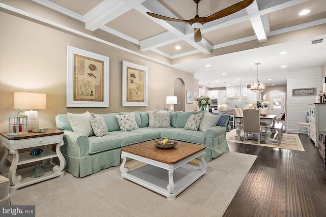 living room with coffered ceiling, ceiling fan with notable chandelier, crown molding, beamed ceiling, and dark hardwood / wood-style flooring