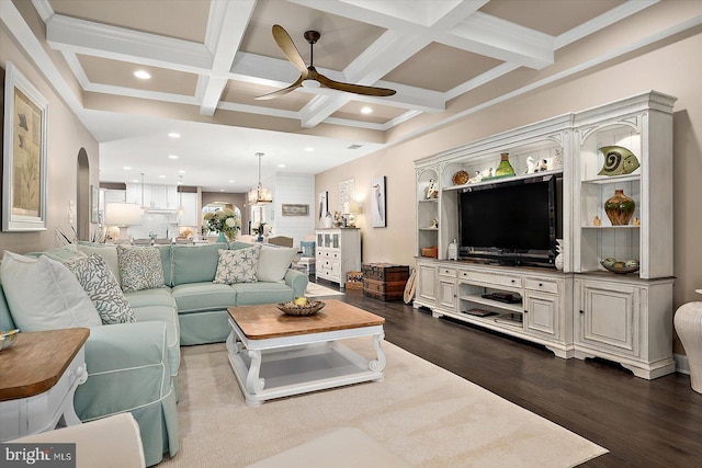 living room featuring coffered ceiling, beamed ceiling, hardwood / wood-style floors, ceiling fan with notable chandelier, and ornamental molding