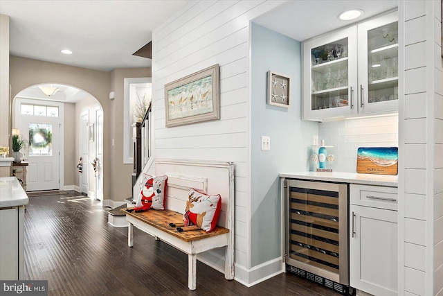 bar featuring white cabinets, backsplash, beverage cooler, and dark wood-type flooring