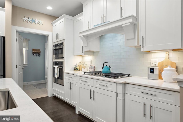 kitchen featuring backsplash, white cabinetry, stainless steel appliances, and light stone counters