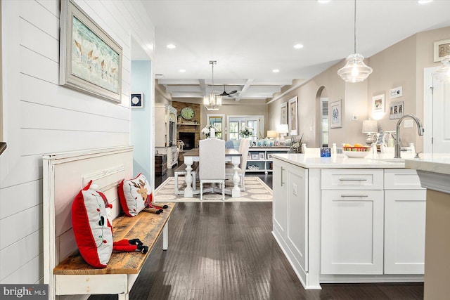 kitchen featuring dark hardwood / wood-style flooring, beamed ceiling, white cabinets, and pendant lighting