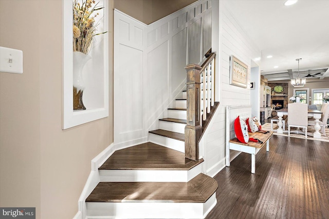 stairway featuring hardwood / wood-style floors, a fireplace, and an inviting chandelier