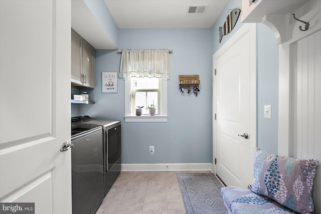 clothes washing area with cabinets, light tile patterned flooring, and washing machine and clothes dryer