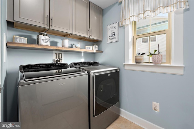 clothes washing area featuring cabinets, independent washer and dryer, and light tile patterned floors