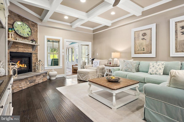 living room with beamed ceiling, ornamental molding, a stone fireplace, and dark wood-type flooring