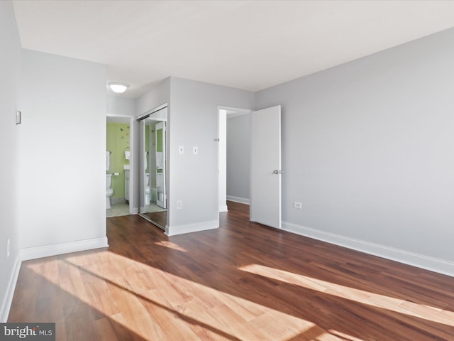 unfurnished bedroom featuring dark hardwood / wood-style flooring, ensuite bath, and a closet