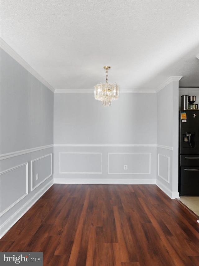 spare room with crown molding, dark hardwood / wood-style flooring, and a notable chandelier