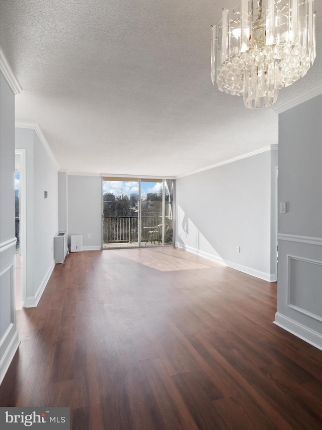 unfurnished living room featuring dark wood-type flooring, floor to ceiling windows, ornamental molding, and a notable chandelier