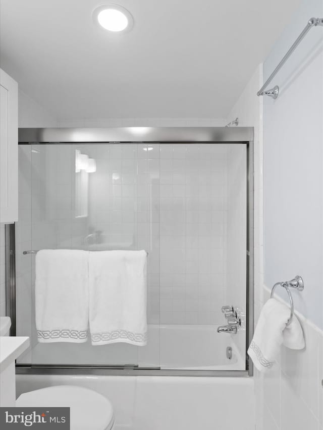 bathroom featuring toilet and combined bath / shower with glass door