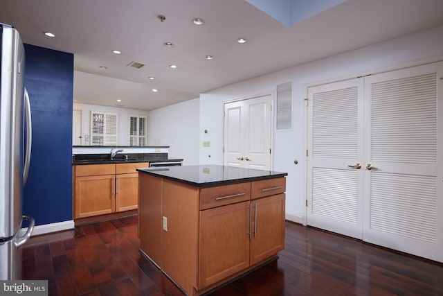 kitchen featuring stainless steel fridge, dark hardwood / wood-style floors, a center island, and sink