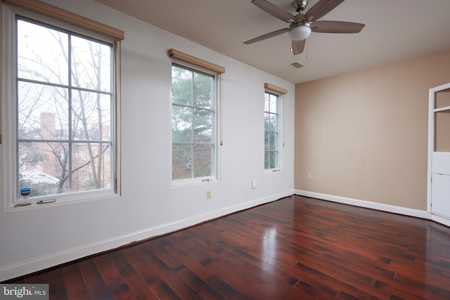 empty room featuring a wealth of natural light, dark wood-type flooring, and ceiling fan