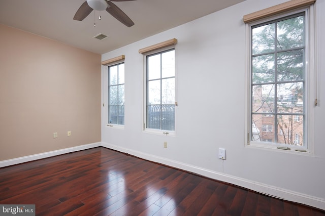 spare room with dark hardwood / wood-style floors, ceiling fan, and a wealth of natural light