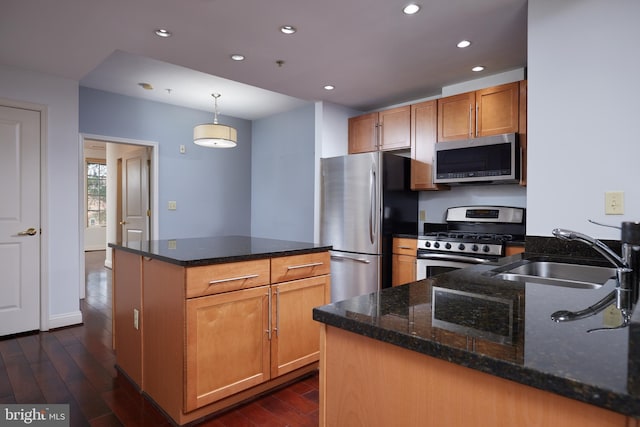 kitchen featuring appliances with stainless steel finishes, hanging light fixtures, dark wood-type flooring, and sink