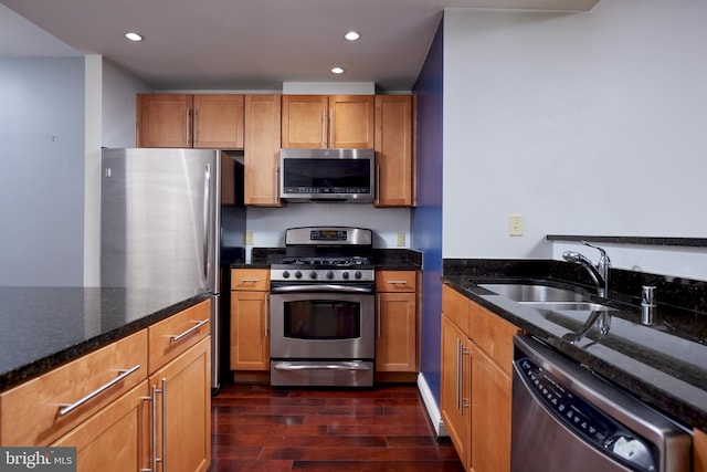 kitchen featuring dark hardwood / wood-style floors, sink, appliances with stainless steel finishes, and dark stone counters