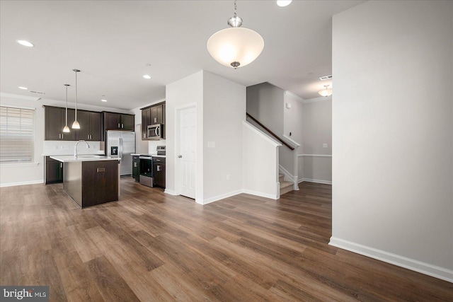 kitchen featuring stainless steel appliances, hanging light fixtures, a center island with sink, and dark hardwood / wood-style floors