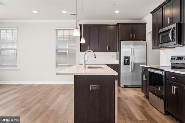 kitchen featuring stainless steel appliances, a kitchen island with sink, a healthy amount of sunlight, and sink