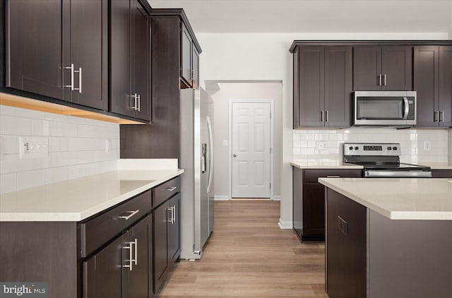 kitchen with dark brown cabinetry, stainless steel appliances, and light wood-type flooring