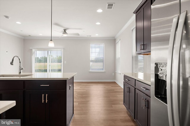 kitchen with stainless steel fridge, light wood-type flooring, crown molding, sink, and hanging light fixtures