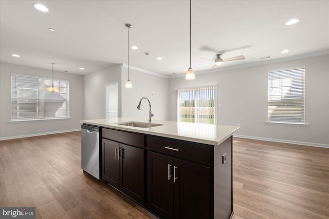 kitchen with stainless steel dishwasher, sink, decorative light fixtures, light hardwood / wood-style flooring, and an island with sink