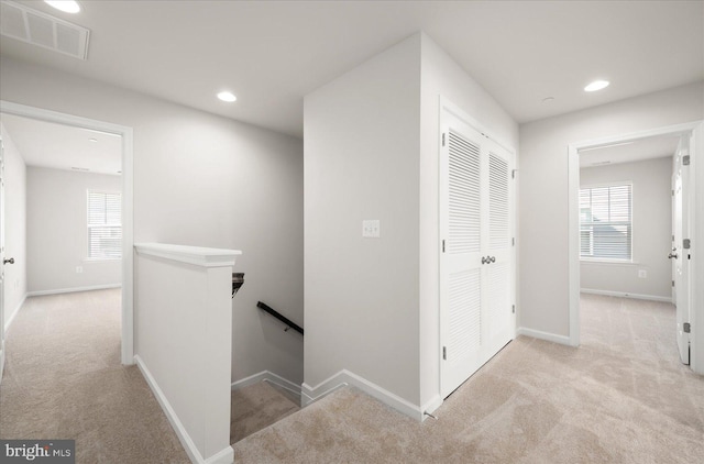 corridor featuring light colored carpet and a wealth of natural light