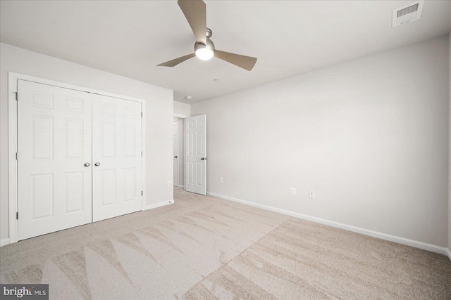 unfurnished bedroom featuring ceiling fan, a closet, and light carpet