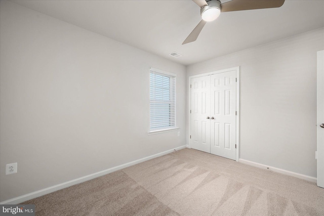 unfurnished bedroom featuring light carpet, a closet, and ceiling fan