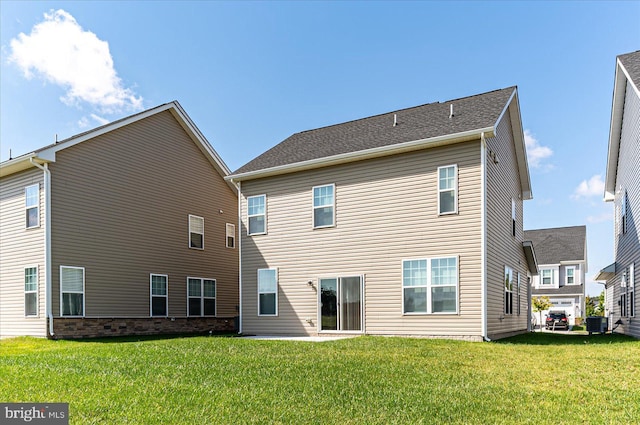 rear view of property with a lawn and central air condition unit