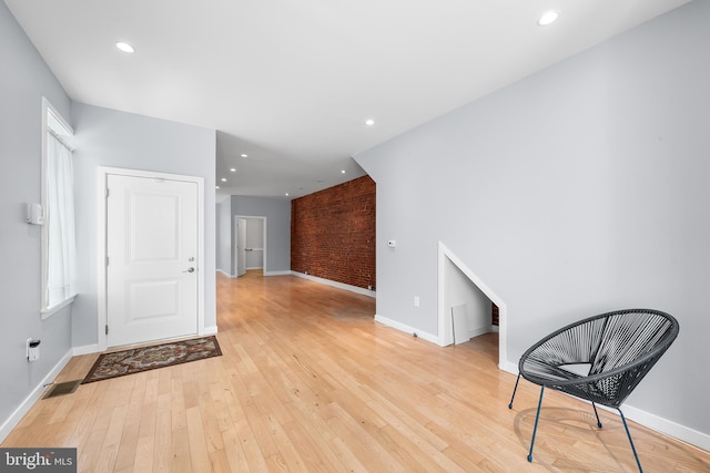 unfurnished room with light hardwood / wood-style flooring and brick wall