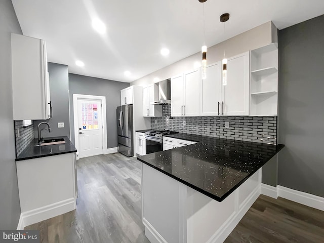 kitchen with pendant lighting, white cabinets, wall chimney range hood, appliances with stainless steel finishes, and kitchen peninsula