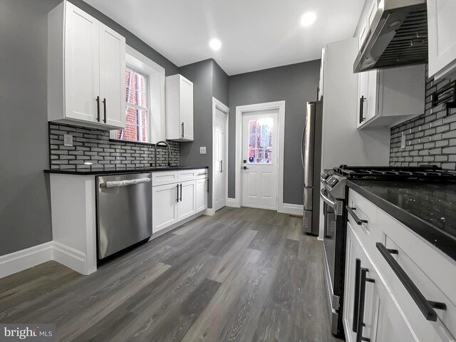 4827 N Warnock St, Philadelphia, PA 19141 - kitchen with wall chimney exhaust hood, stainless steel appliances, light wood-type flooring, and decorative backsplash