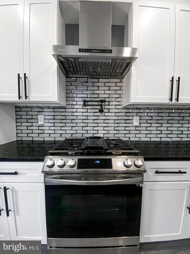 kitchen with wall chimney exhaust hood, stainless steel gas stove, and white cabinets